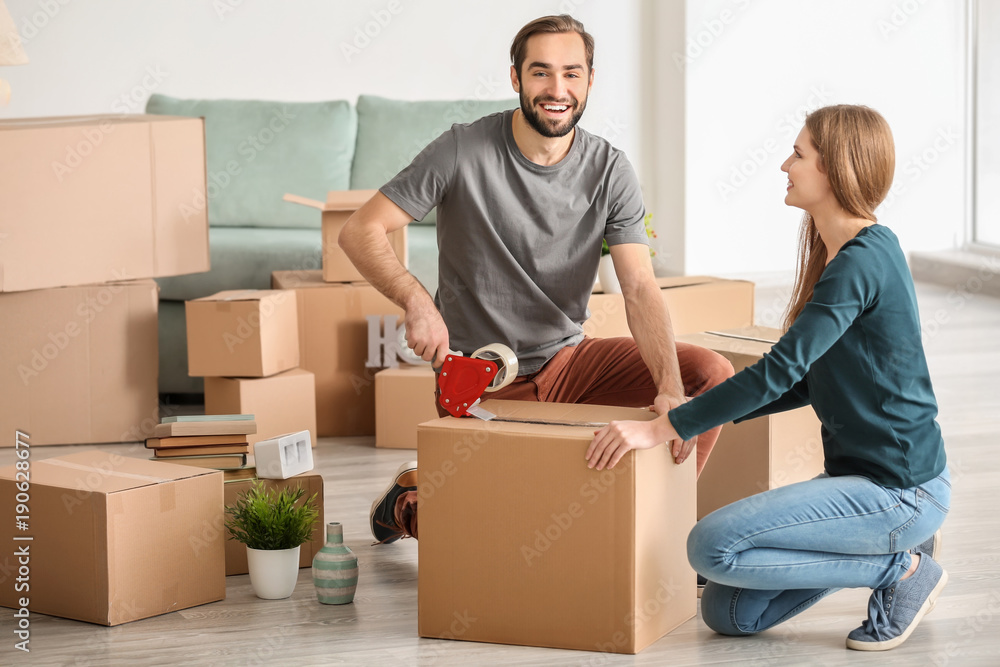 Wall mural Young couple packing moving boxes, indoors