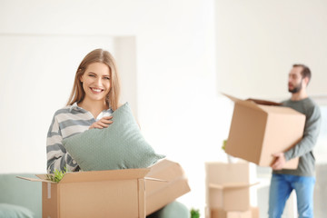 Young woman with moving box in room at new home