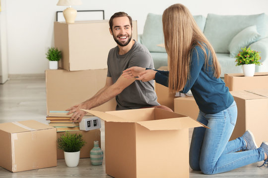Young couple packing moving boxes in room