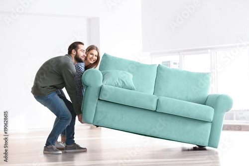 Young Moving Sofa In Room At New Home Stock Photo