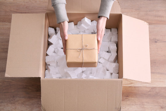 Woman taking gift box out of parcel indoors