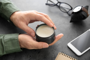 Man with jar of clay for hair at table, closeup