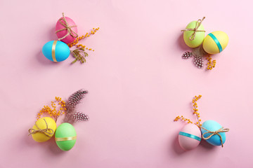 Decorated Easter eggs and mimosa on color background