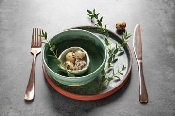 Beautiful festive Easter table setting with quail eggs on gray background