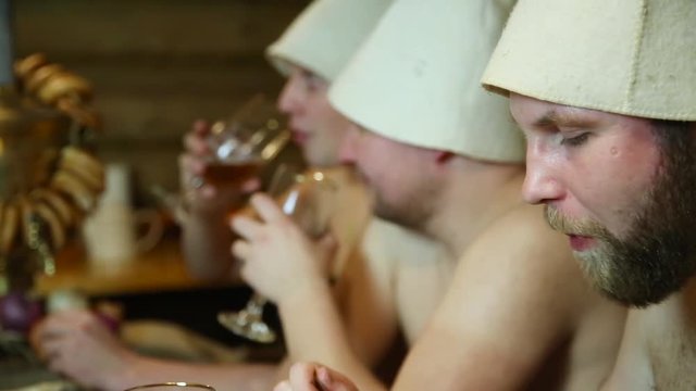 men friends eats meat kebabs and drinking beer, relaxing in the bathhouse