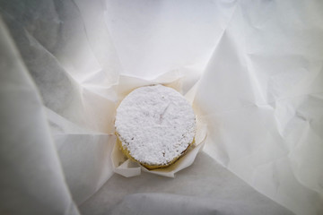 Primo piano di un delizioso pasticcino ricoperto con zucchero a velo dentro un bianco sacchetto di carta