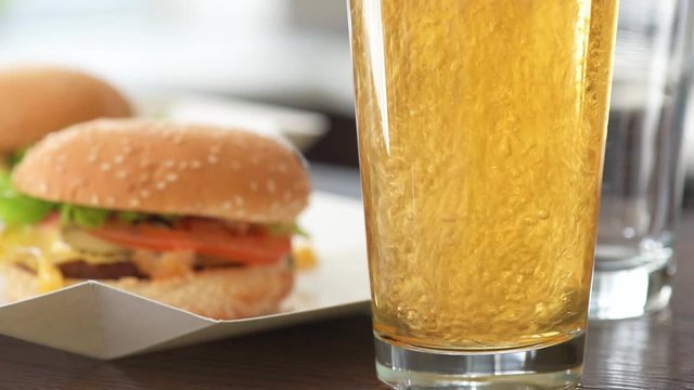 Cinemagraph - Pouring Light Beer Into Glass. Two Hamburger With Fresh Vegetables And Beer Glasses. Motion Photo.