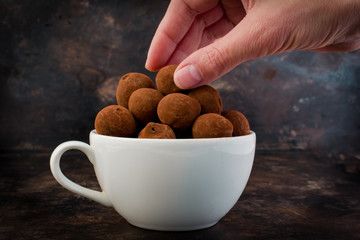 HAND TAKING A CHOCOLATE TRUFFLE DESSERT FROM A COFFE ECUP