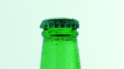 The neck of a green bottle with a cold drink. Covered with droplets of water
