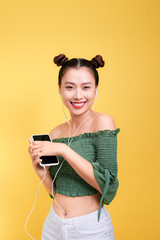 Colorful studio portrait of happy young asian woman with earphones is dancing and singing.