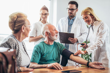 Image of young medic taking blood pressure during home visit
