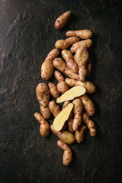 Raw uncooked organic potatoes named bayard, whole and slice over dark texture background. Top view, copy space