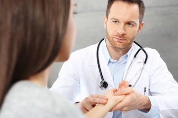 Wizyta u lekarza.Lekarz bada tętno pacjenta trzymając go za nadgarstek.
