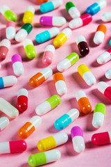 different color pills on a pink background. Drugs and medicines, concept