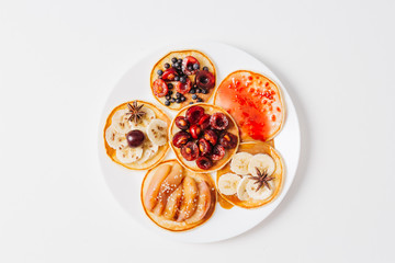 Baked pancakes or homemade cakes. On top is decorated with berries, fruits, honey and jam on rustic background. top view. close up. Chalk plaque