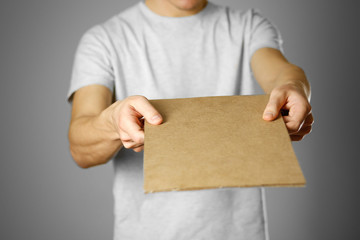 A young guy in a white t-shirt holding a piece of cardboard. Prepared for your text