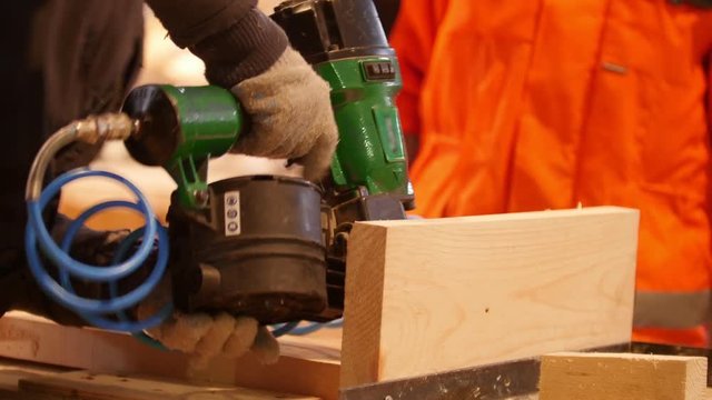 Construction workers fixing board with pneumatic nail gun
