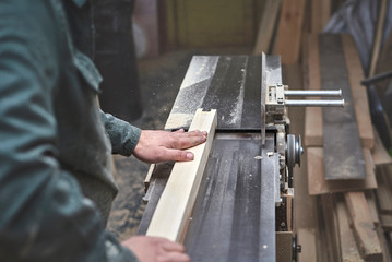 the man processes bar from a light tree on the jointer plane