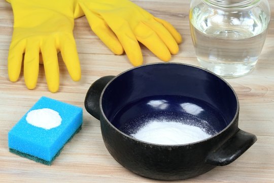 Natural cleaners for burnt meal in pot. Baking soda (sodium bicarbonate), water,  sponge 