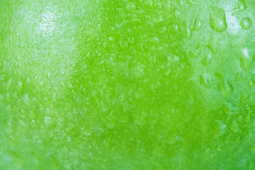 Water drops background on a green apple surface in close-up