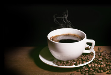 Coffee cup with saucer and beans on wooden table