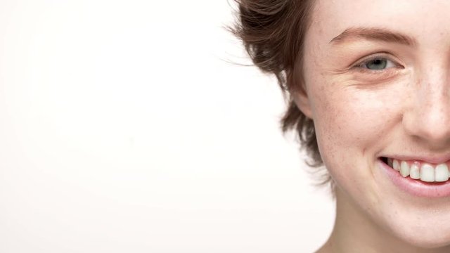 Half-side portrait of joyful woman with freckle and short hair looking on camera with smile, isolated over white background closeup. Concept of emotions