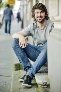 Portrait of smiling young man sitting on step outdoors