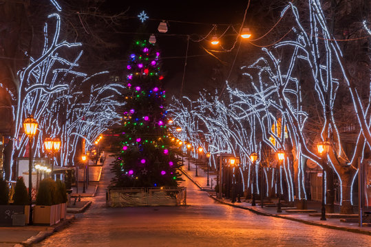 Decorated with lights, garlands of Christmas tree, the central old street of the city. Night photo. A row of old street lamps. Odessa. Ukraine. Deribasovskaya street.

