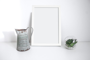 A4 white frame on desk with plant and vintage jug