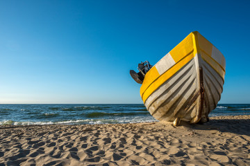 samotna żółta łódź na plaży - obrazy, fototapety, plakaty
