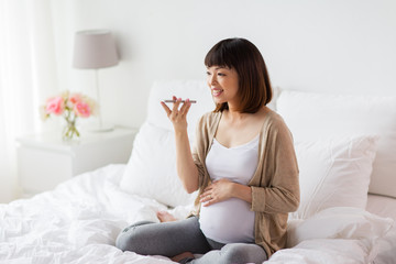 Obraz na płótnie Canvas pregnant woman using voice recorder on smartphone