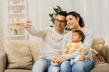 mother and father with baby taking selfie at home