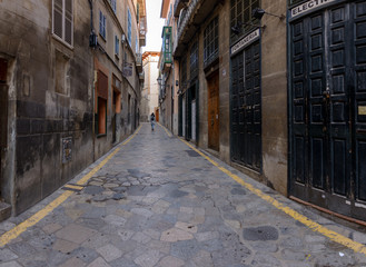 Fototapeta na wymiar Old shops and old streets in the center of Palma city. Girl walking away