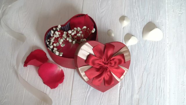 Gift box in form of heart and red ribbon on wooden white background. Top view