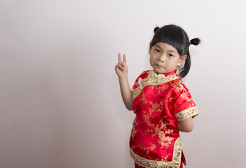 Little girl in Chinese dress. Little girl with gesture of victory. Look at camera.