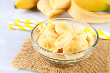 Bananas are whole and cut on a slice in a cup on a gray background.