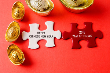 Gold ingots and white puzzle for Chinese New Year festive decorations on a red background. Chinese...