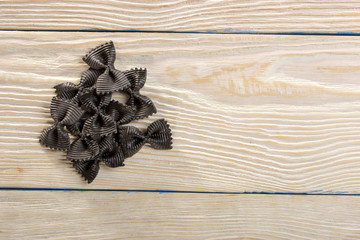 A small bunch of pasta in the shape of a butterfly on a wooden background