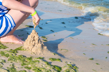 girl making a sand castle on the beach near the sea.