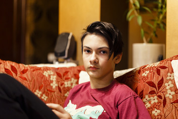 a boy sitting on the couch and playing with a rubik cube
