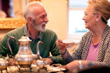 Beautiful senior couple smiling and drinking tea at nursing home