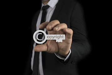 Businessman in his hands copyright key icon over blur colorful, Copyright and patents concept