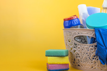 Basket with cleaning items on yellow background. Cleaning and housekeeping concept. copy space.