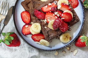 Homemade Chocolate Waffles topped with fresh berries ans banana