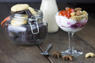 Yogurt with topping tomato almond cashew nut in wine glass with milk on wooden table.