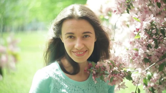 Beautiful lovely and young woman at the flowers of tree branches in spring