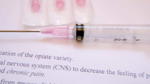 Tracking shot with a syringe and words about painkiller morphine  opioids.