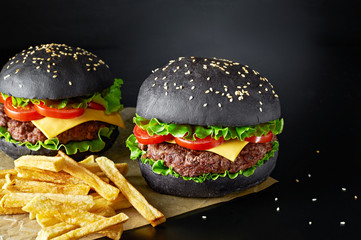 Black beef burger with french fries isolated on black background