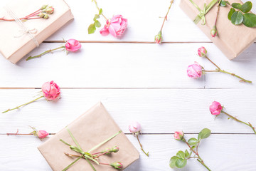 Flowers composition. Workspace with rose flowers, gift, paper bag. Top view, flat lay.