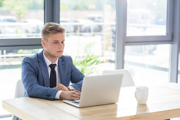 Young businessman looking at laptop screen in modern office